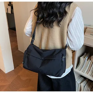 Détail d'un grand sac bandoulière noir en nylon avec sangle réglable porté par un mannequin