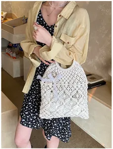 Détail d'un sac cabas tissé blanc ajouré avec nœud en dentelle et chaîne de perles chic