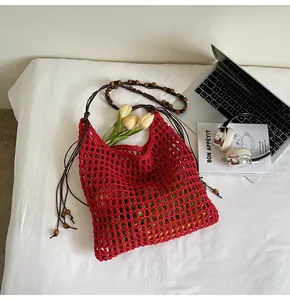 Detail of red hollow crochet tote bag featuring wooden bead shoulder straps and net texture