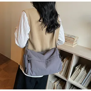 Détail du grand sac bandoulière en nylon mauve avec plusieurs poches zippées