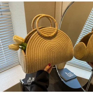 Detail einer beigen halbrunden Strohtasche mit runden Griffen und Tulpendekoration