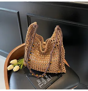 Detail of hollow straw tote bag featuring beaded shoulder straps and a white fabric liner