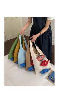 Detail of colorful knitted tote bags with 3D fish dolls in various cream pastel colors