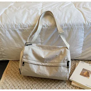 Détail du sac polochon en nylon crème montrant le tissu texturé et les fermetures éclair