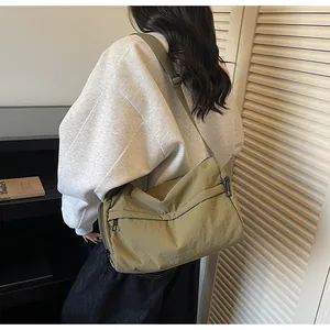 Vue détaillée d'un sac bandoulière en nylon vert olive porté avec sangle réglable