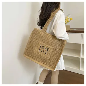 Detail view of woven beach tote bag featuring LOVE LIFE embroidery and long shoulder straps