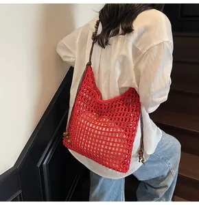 Detail of red hollow straw shoulder bag with wooden beads and woven mesh pattern