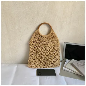 Gros plan détaillé du sac cabas en macramé tissé avec poignée ronde en bois sur blanc