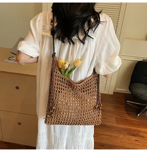 Detail of hollow straw tote bag with decorative wooden beads and long tassels