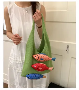 Detail of green knitted tote bag with 3D colorful fish patches worn by a model