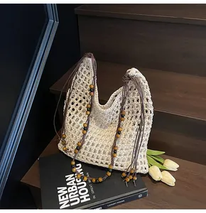 Detail of hollow straw tote bag featuring decorative wooden beads and cotton mesh