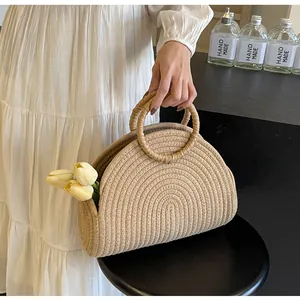 Detail of a handmade straw tote bag with semi-circular woven body and round top handles