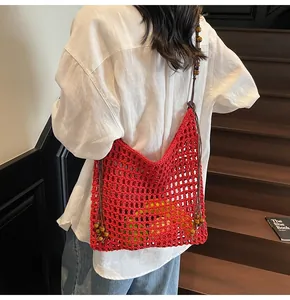 Detail of red hollow mesh woven beach bag with wooden beads and shoulder strap
