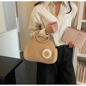 Detail der handgewebten Strohtasche mit Rundgriff und weißem 3D-Gänseblümchen-Akzent