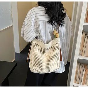 Gros plan sur un cabas en crochet beige avec lanières en cuir marron et fleurs