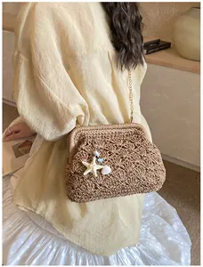 Detail of woven straw bag with starfish charms and gold chain strap for summer beach