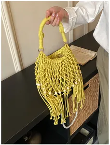 Macro detail of bohemian yellow woven bag featuring cotton fringe and wood bead accents