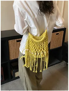 Detail of yellow woven tassel bag with pearl strap and wooden beads on neutral background