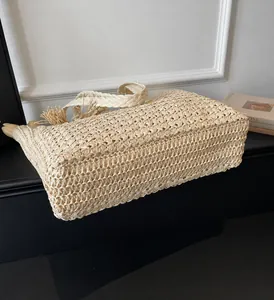 Détails du sac de plage en paille avec motifs tressés et pompons décoratifs