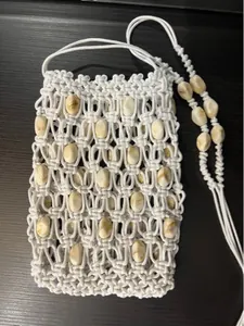 Close-up of bohemian white macramé phone bag with marble beads and woven shoulder strap