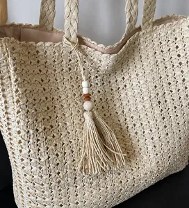 Détail du sac de plage en paille avec pompon bohème et perles en bois décoratives