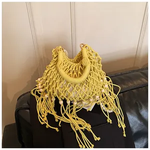 Detail of yellow hollow knit beach bag with wood beads, long tassels and white lace lining
