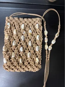 Detail view of bohemian hand-woven mini bag with marble beads and fringe on dark wood