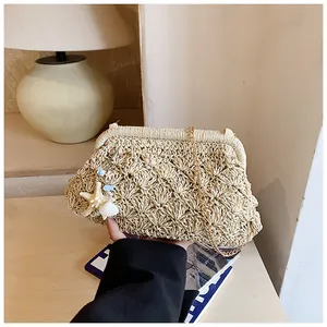 Detail of straw woven clutch with ocean charms and elegant gold metal chain