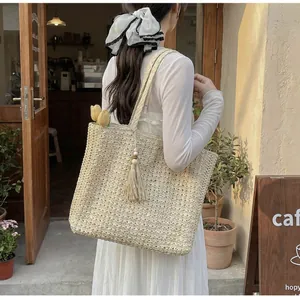 Détail d'un grand sac cabas beige en crochet avec pompons dans un cadre de style de vie