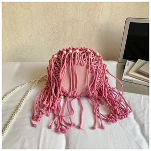 Detail of pink hand-woven bucket bag with fringe, wooden beads and pearl shoulder strap