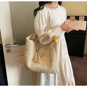 Détail du sac cabas en paille avec des glands élégants et une texture tricotée