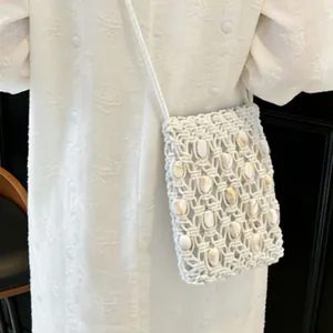 Detailed texture of white woven crossbody bag featuring bohemian shell embellishments