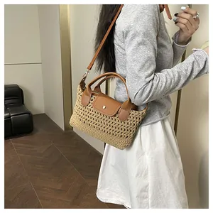 Detail of woven straw handbag featuring brown leather flap and golden button buckle