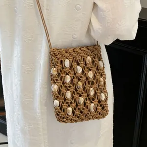 Detail of bohemian hand-woven mini bag with decorative shells and crochet pattern