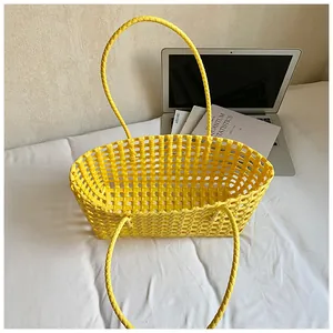 Détail d'un sac de plage tressé jaune avec de longues poignées et un design à mailles vides