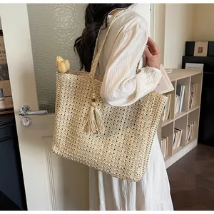 Détail d'un grand sac cabas en paille avec texture tissée et pompons en coton