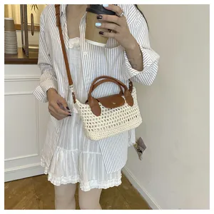 Detail of hand-woven beige knit bag with brown leather strap and metal buckle on a model