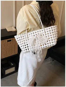 Détail du sac panier tressé avec un grand nœud en dentelle blanche brodée