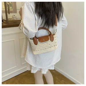Detail of hand-woven straw crossbody bag with brown leather flap and metal buckle strap