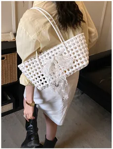 Détail du sac de plage ajouré blanc avec un grand nœud en dentelle et bandoulière tressée