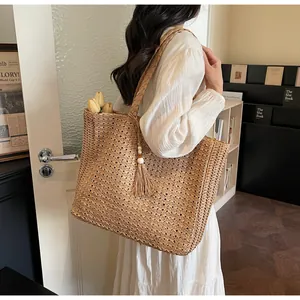 Gros plan du sac fourre-tout en paille tissée avec texture détaillée et pompon à perles de bois blanc