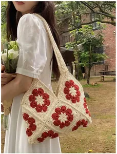 Detail of hand-woven crochet shoulder bag with 3D red flowers on cream base