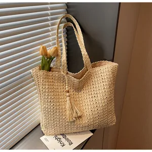 Détail du sac cabas en paille tissée avec glands et perles de bois pour style de plage