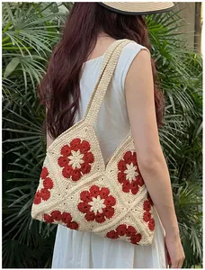 Detail of handmade crochet shoulder bag featuring floral granny square patterns in rust red