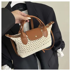 Close-up of woven cream handbag with brown leather flap and golden metal buckle detail