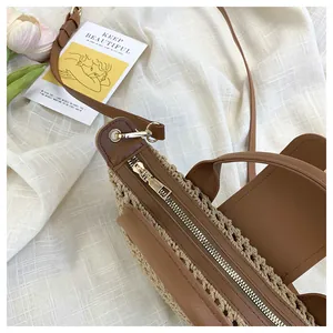 Detailed close-up of woven beige texture and brown leather trim with metal zipper
