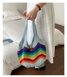 Detailaufnahme der gestrickten Regenbogen-Tasche mit einem braunen Lederanhänger