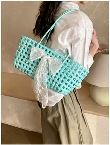 Détail d'un sac cabas tressé vert menthe avec un grand nœud en dentelle blanche et maille