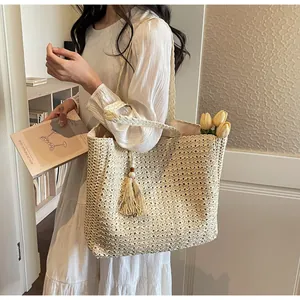 Détail du sac cabas en paille tissé avec anses tressées et glands décoratifs