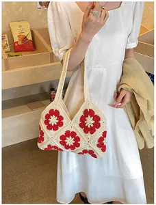 Detailed close-up of handmade crochet bag featuring red 3D floral patterns and woven straps